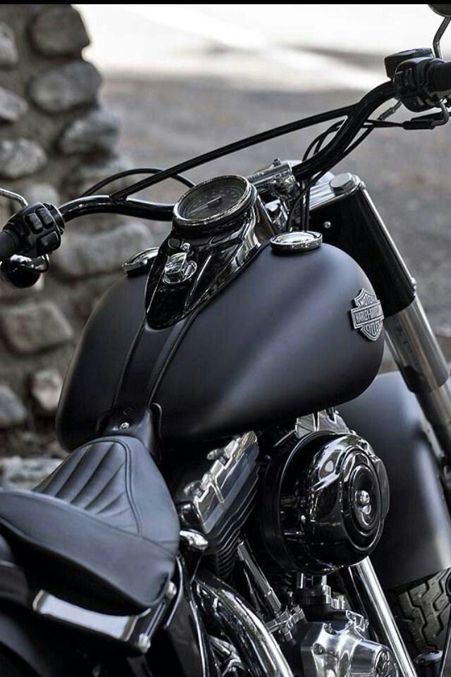 a black and white photo of a motorcycle parked in front of a stone wall,