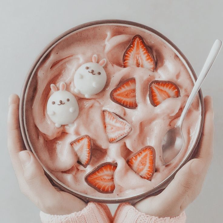 a person holding a bowl of yogurt with strawberries and ghost faces on it