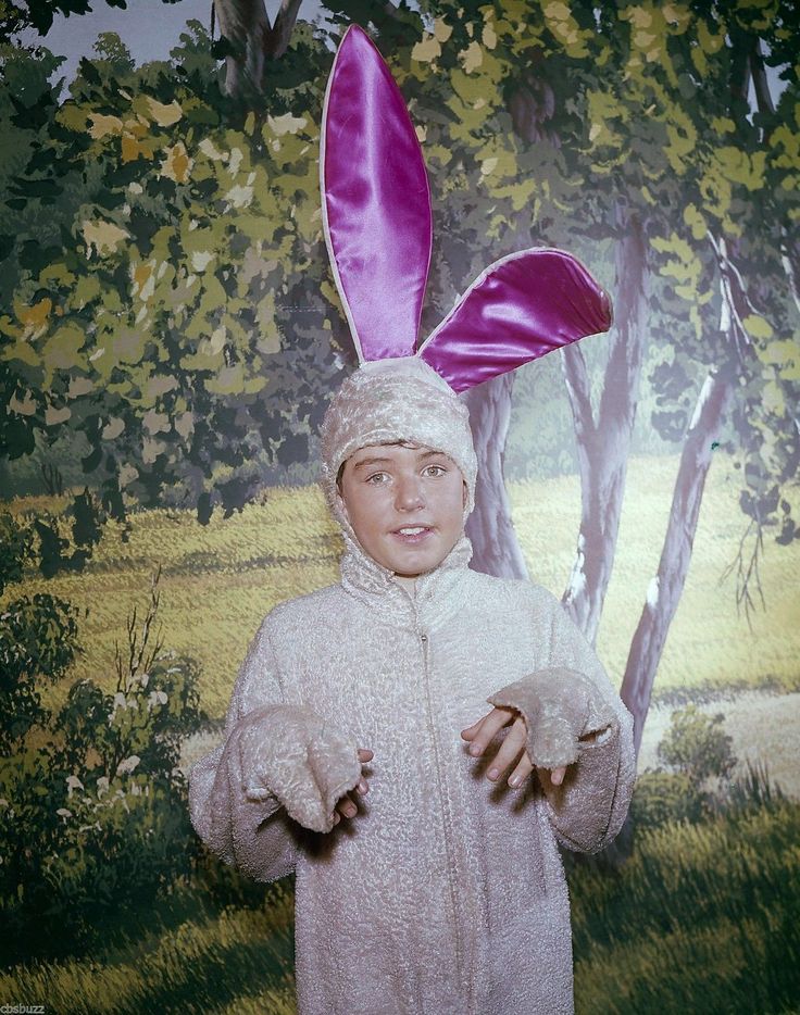 a young boy dressed up in an easter bunny costume and holding out his hand to the camera