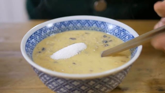 a bowl of soup with a spoon in it on a wooden table next to a person