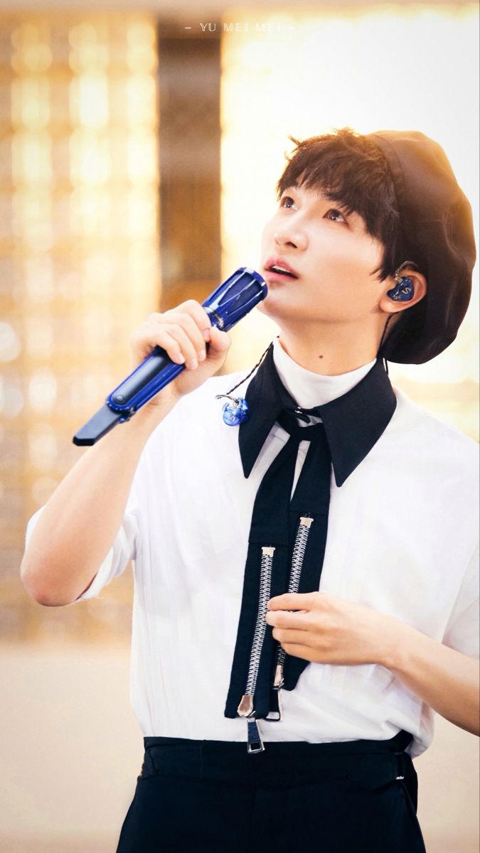 a young man wearing a hat and tie brushing his teeth with an electric toothbrush