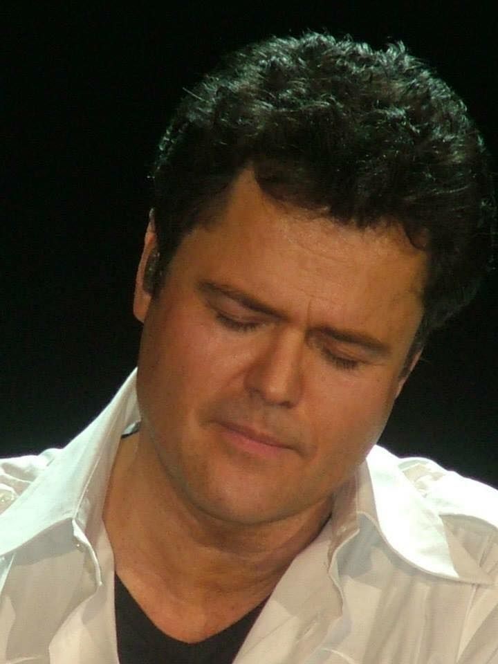 a close up of a person wearing a white shirt and looking at his cell phone