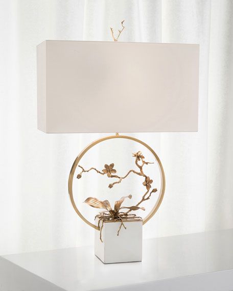 a table lamp with a white shade on top of it and flowers in the center