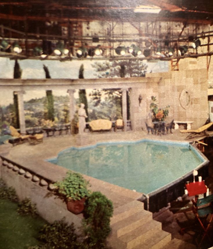 an indoor swimming pool in the middle of a room with many chairs and tables around it