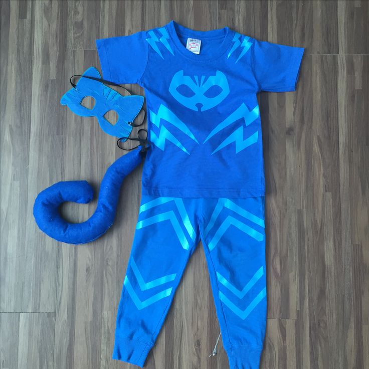 a blue costume and mask laying on the floor next to a pair of scissors,