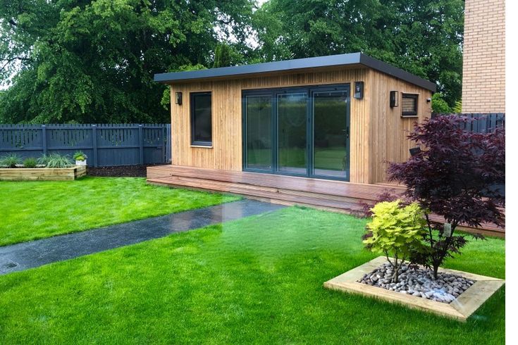 a small wooden building sitting on top of a lush green field next to a tree