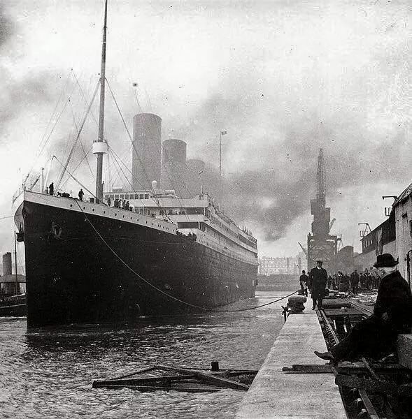 a man sitting on a bench next to a large ship