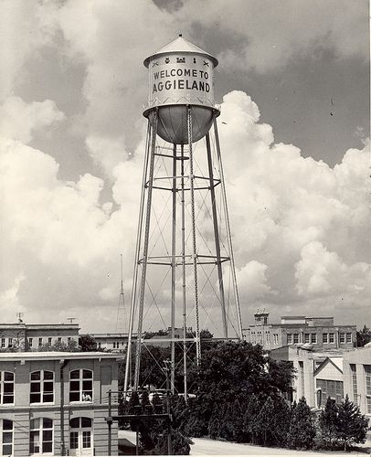 an old water tower with the words welcome to aggieland on it's side