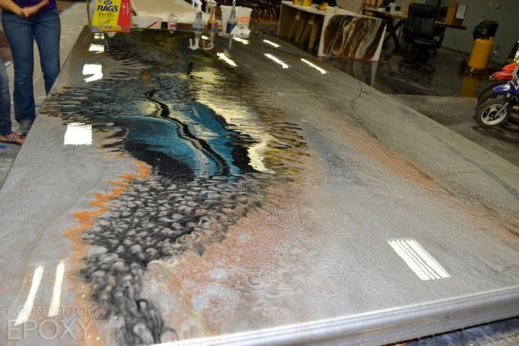 a woman standing next to a large table covered in art on the side of it