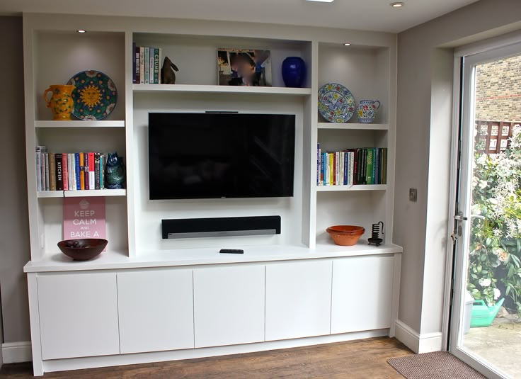 a flat screen tv sitting on top of a white entertainment center next to a sliding glass door