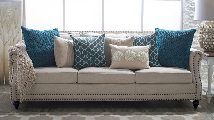 a living room scene with focus on the couch and pillows in front of the window