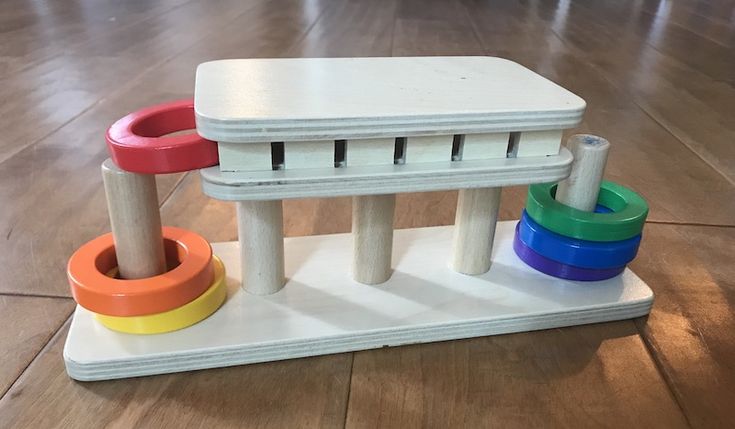 a white table with colorful plastic rings on the top and two stools sitting in front of it