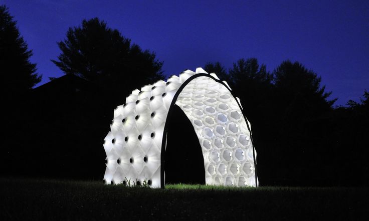 a large white sculpture sitting on top of a lush green field under a blue sky