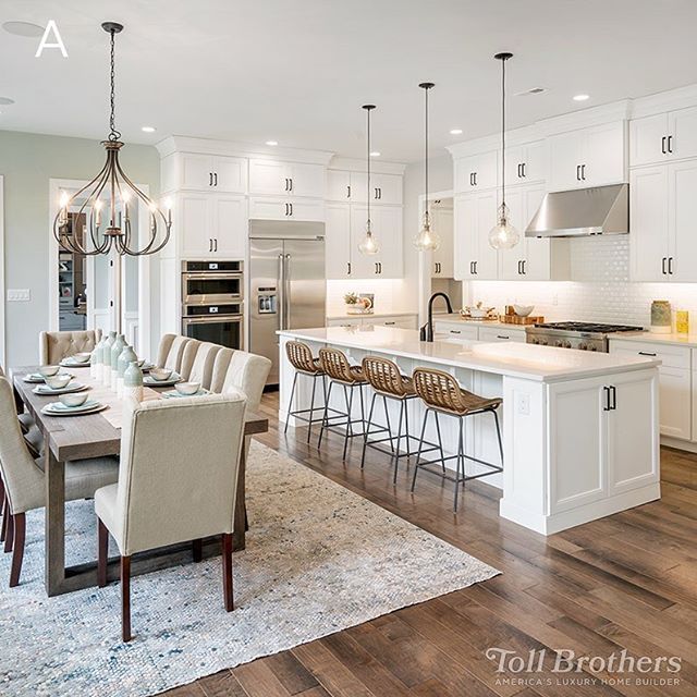 a large kitchen with white cabinets and an island in front of the dining room table