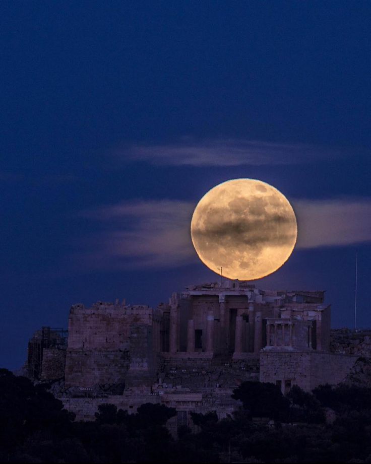 the full moon is seen over an ancient building