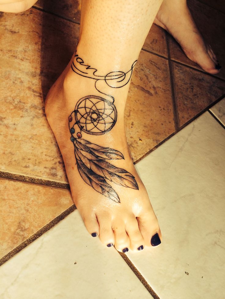 a woman's foot with a tattoo on it and a dream catcher in the middle