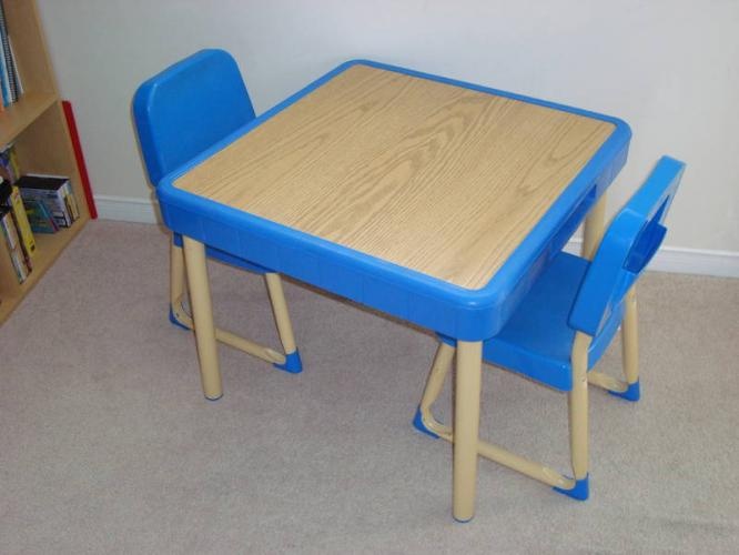 a wooden table and two blue plastic chairs