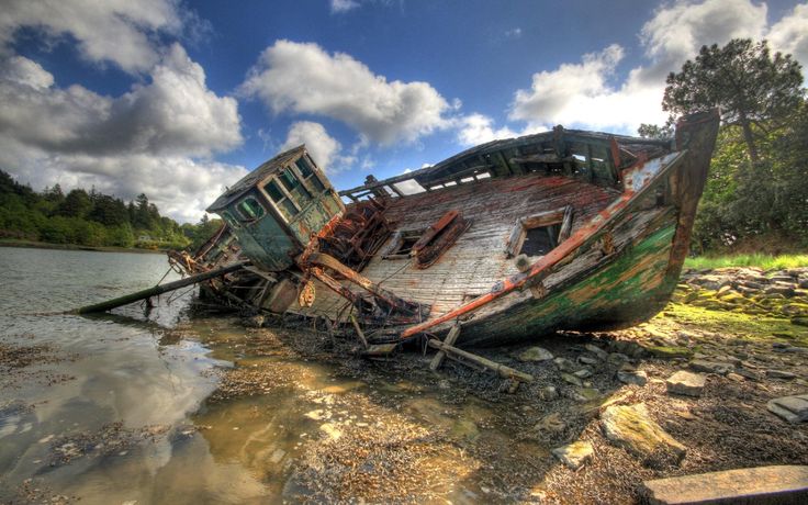 an old abandoned boat sitting on the shore