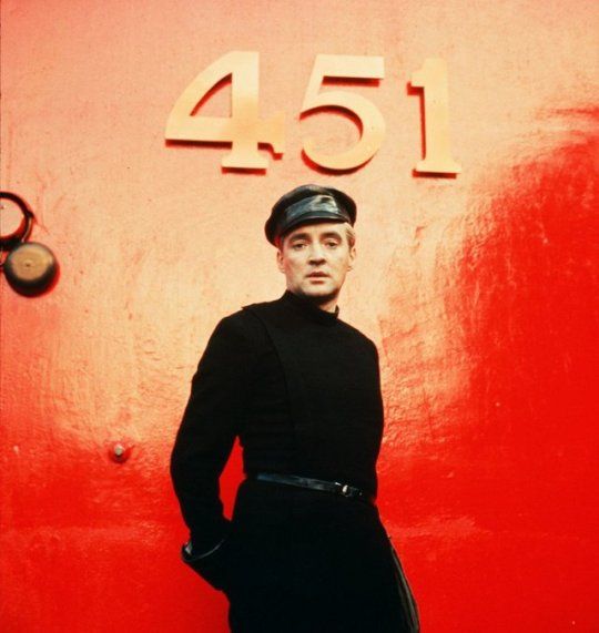 a man standing in front of a red wall with the number forty4 on it