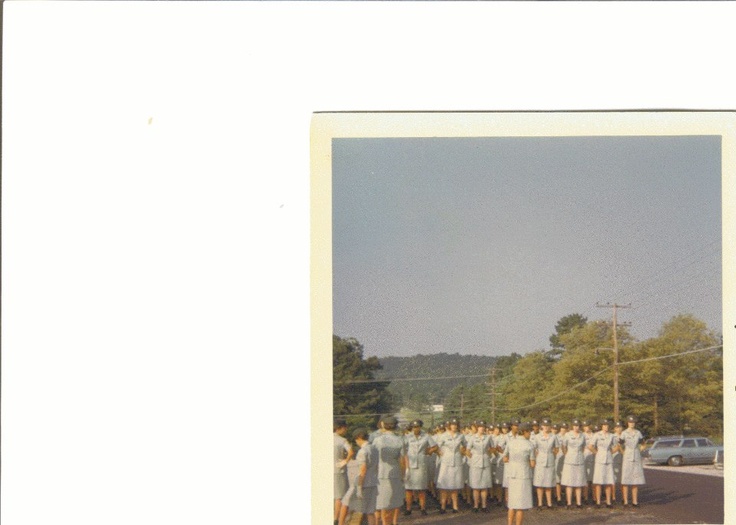 a group of women in white dresses standing next to each other on the side of a road