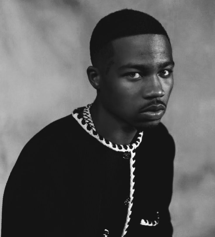 a black and white photo of a young man in a sweater looking at the camera