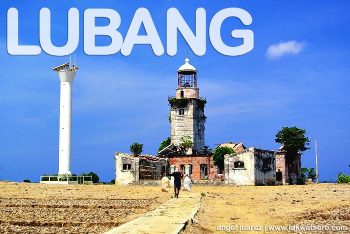 a man walking down a dirt road next to a tall white tower with the word lubang in front of it