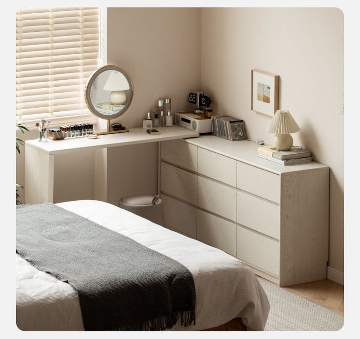 a bedroom with a bed, dresser and mirror in it's corner area next to a window