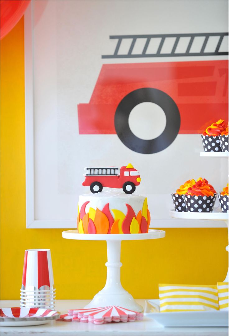 a firetruck themed birthday party with cupcakes and cake on the table