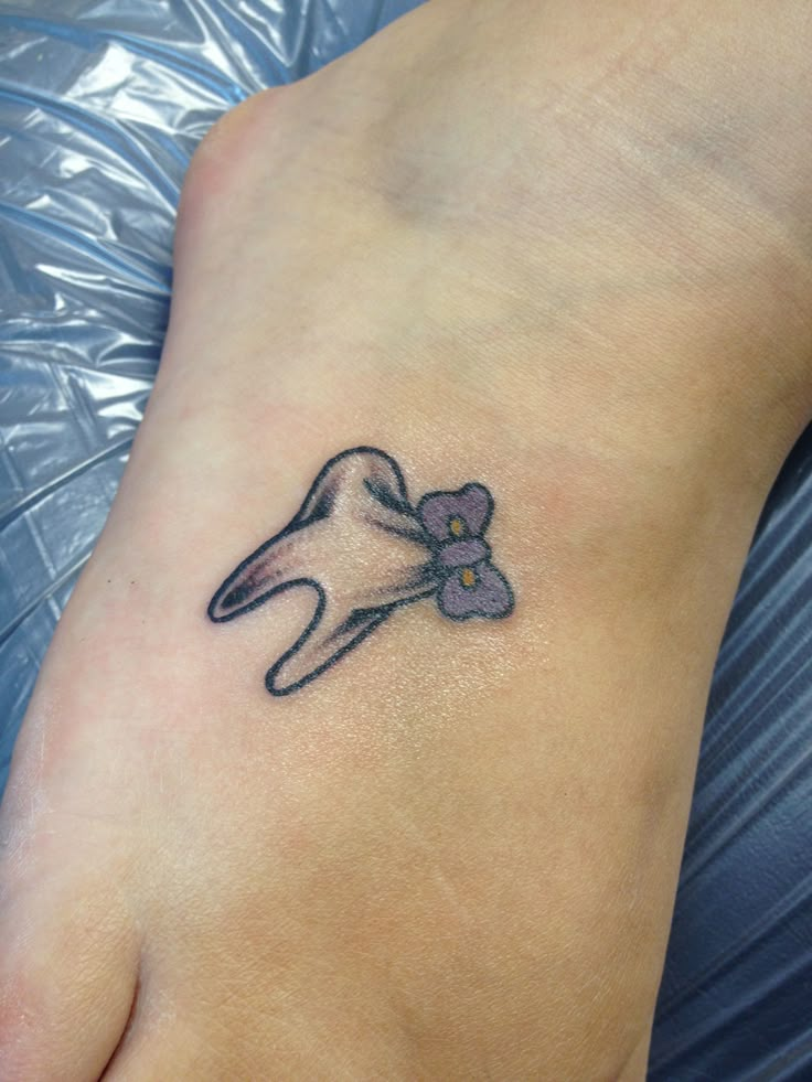 a small foot with a flower tattoo on it