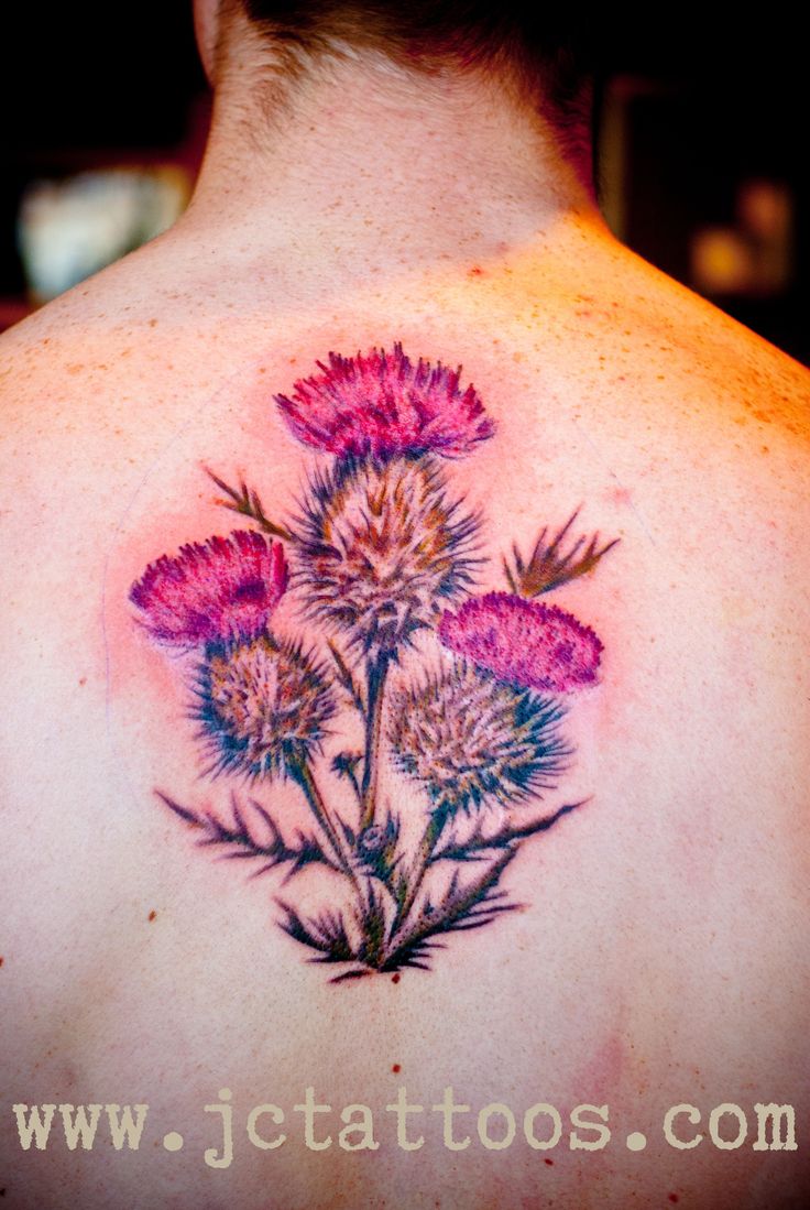 the back of a man's neck with tattoos on it and flowers in the center