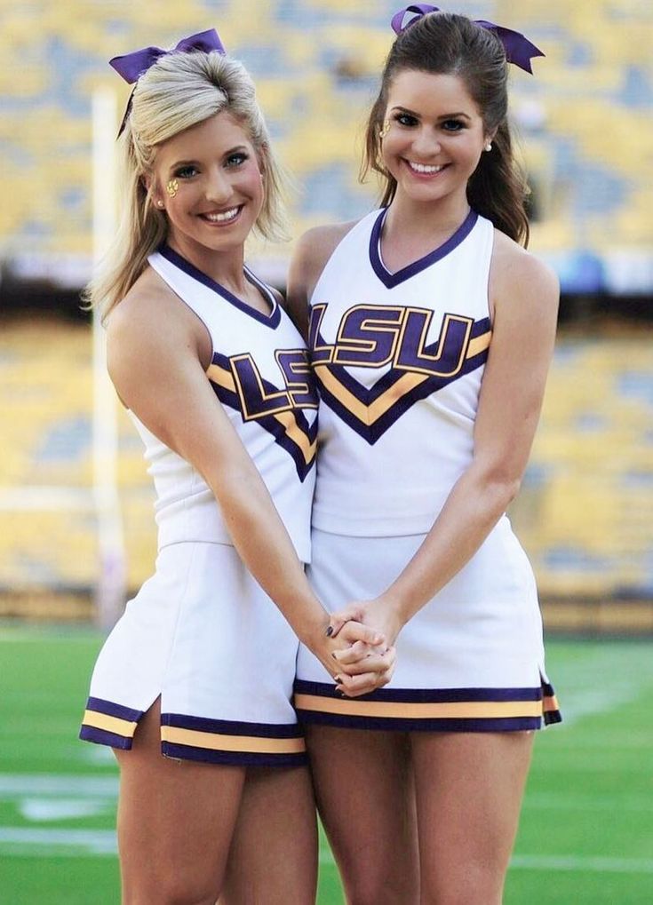 two cheerleaders are standing together on the field