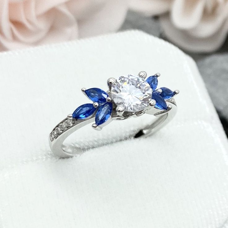 a diamond and blue sapphire ring sitting on top of a white cloth