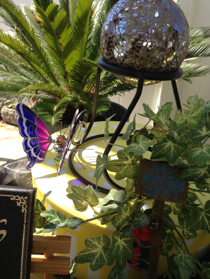 a table topped with lots of green plants next to a mirror ball on top of a metal stand