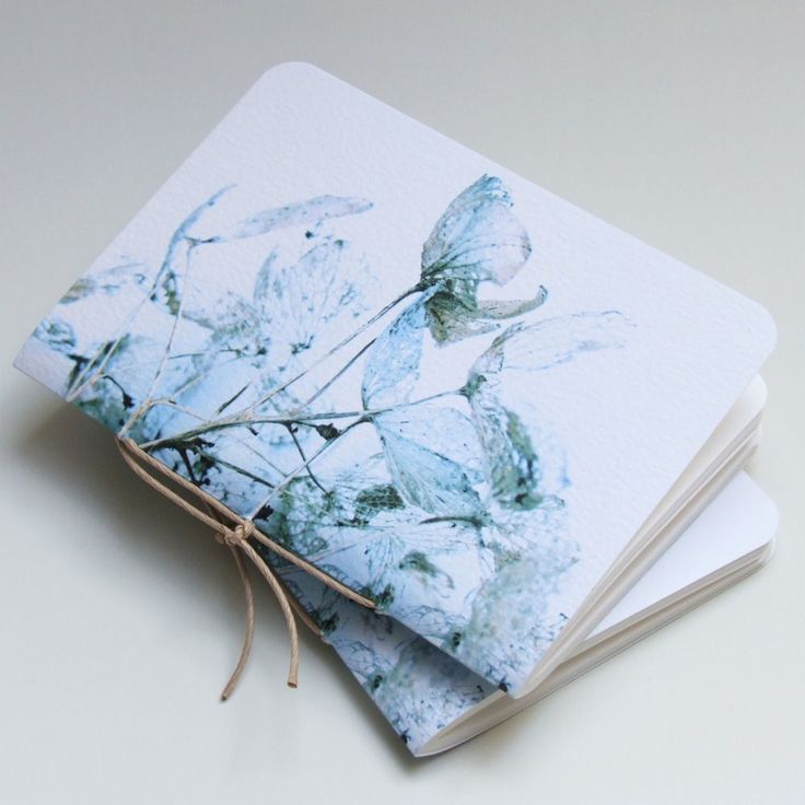 three notebooks with blue flowers on them sitting next to each other and tied together