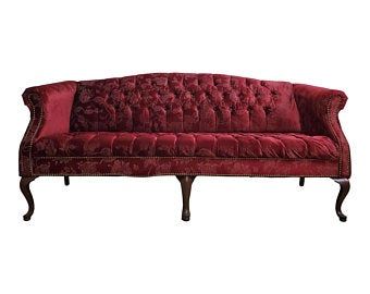 a red velvet couch sitting on top of a wooden frame