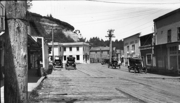 an old black and white photo of cars driving down the street