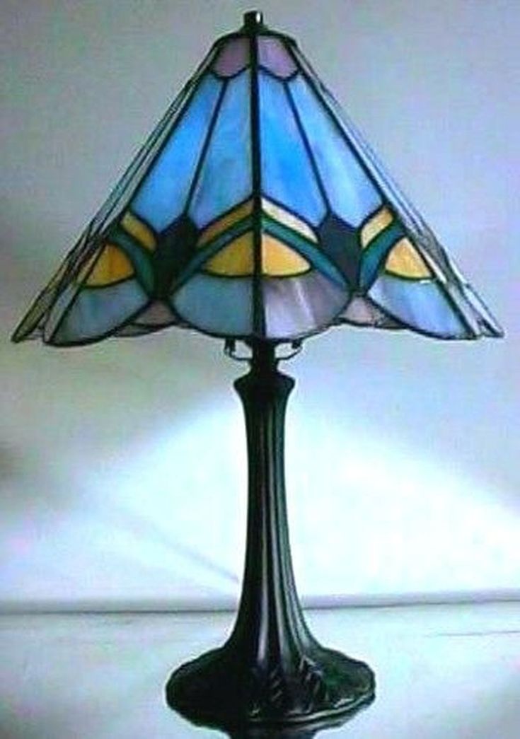 a stained glass lamp on a table with a white wall in the backround