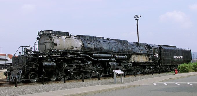 an old train sitting on the tracks next to a street light and some people standing near it