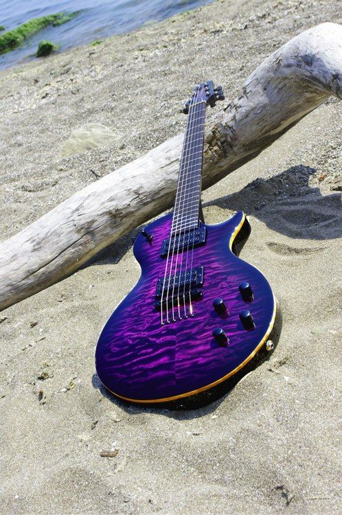 a purple guitar sitting on top of a sandy beach