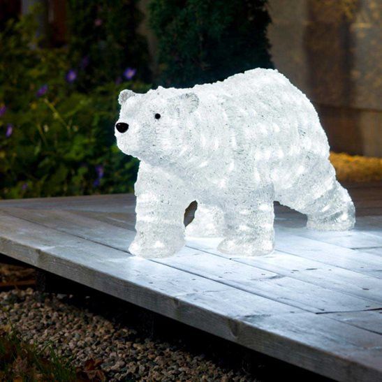 a white polar bear light sitting on top of a wooden platform in front of a house