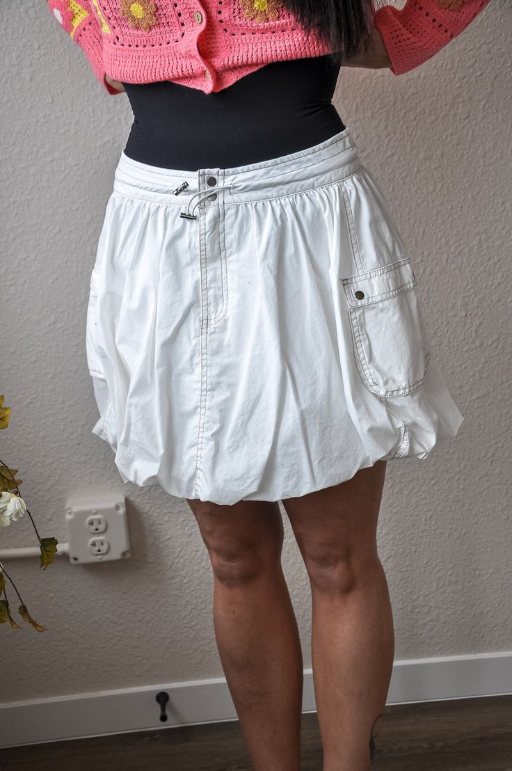 The Drawstring Waist Puff Mini Skirt combines utility and style in a chic and versatile design. Crafted entirely from 100% cotton, this solid mini skirt offers a breathable and comfortable wear for all-day comfort. Its standout feature is the cinch drawstring waistline with a button closure, allowing for an adjustable and customized fit. The addition of two side cargo pockets adds a touch of practicality and a hint of utilitarian charm to the skirt. The puff body silhouette lends a playful and feminine flair, enhancing its overall appeal. Whether paired with a casual tee for a relaxed look or dressed up with a blouse for a more polished ensemble, this mini skirt effortlessly transitions from day to night and from casual to semi-formal occasions. With its blend of comfort, functionality, an Casual Tiered Skirt With Built-in Shorts, Casual Mini Skirt With Built-in Shorts And Relaxed Fit, Casual Mini Skort With Drawstring, Casual Mini Cargo Skirt With Elastic Waistband, Cotton Skirt With Built-in Shorts, Casual Mini-length Skort With Drawstring, Cotton Drawstring Tiered Skirt, Casual Mini Skirt With Drawstring, Casual Mini Cargo Skirt For Spring