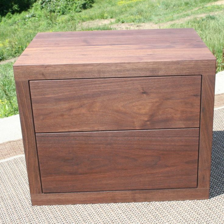 a brown wooden box sitting on top of a carpet next to a grass covered field