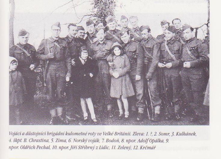 an old black and white photo of people posing for a group shot in front of a tree