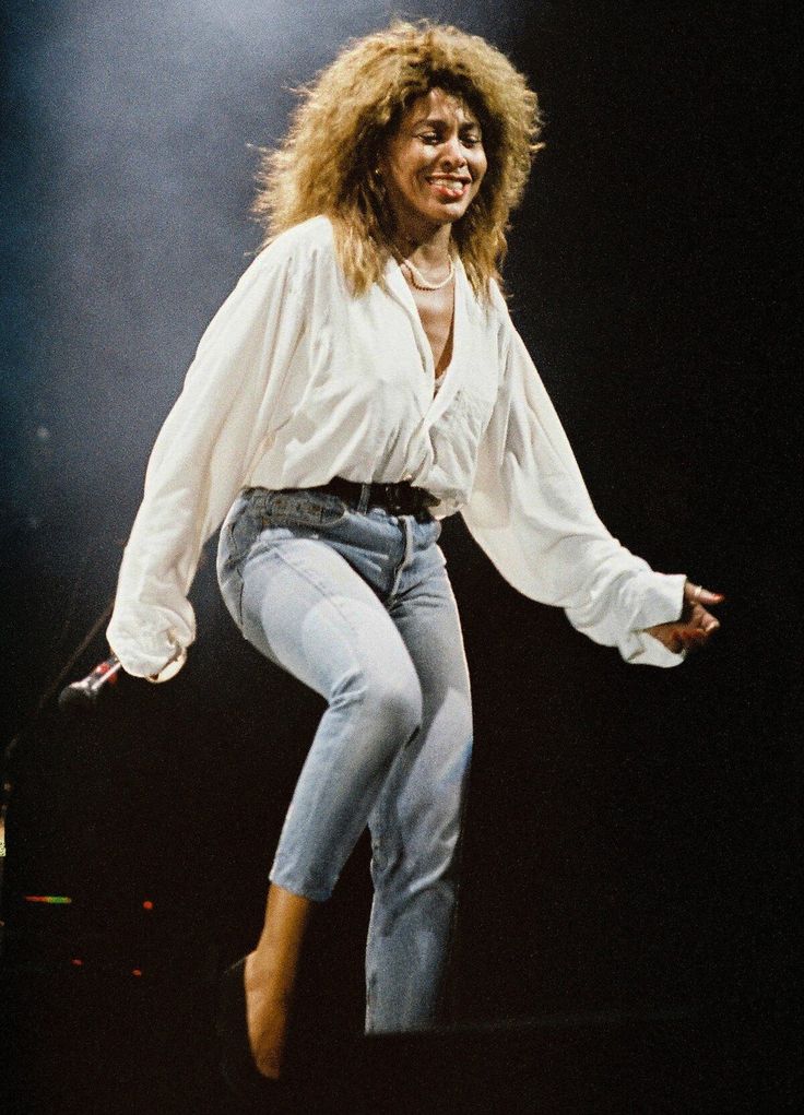 a woman in white shirt and jeans on stage