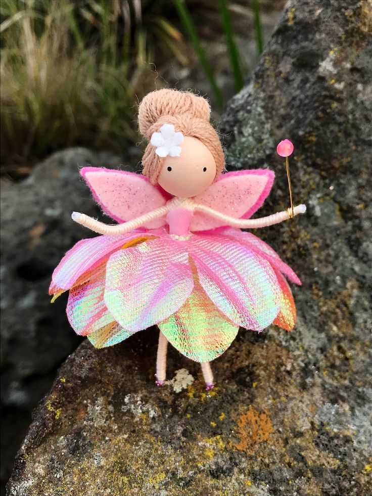 a small toy fairy sitting on top of a rock