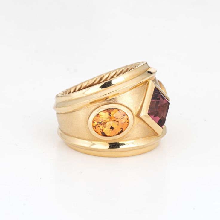 This is part of Chairish’s Fine Jewelry assortment.  Estate David Yurman Renaissance ring crafted in 18 karat yellow.    The out of production David Yurman ring is set with a center set Rhodolite garnet measuring 6mm. Two citrines measure 7mm x 5.5mm. The gemstones are in very good condition and free of cracks or chips. Weighing a hefty 16.6 grams the ring makes a great statement on the hand. The ring has a medium rise (6.5mm - 0.25 inches).  The ring is in very good condition and was recently l Luxury Gold Ruby Ring With Accent Stones, Gold Heirloom Ruby Ring With Gemstone Accents, Heirloom Gold Ruby Ring With Gemstone Accents, Gold Sapphire Ring With Gemstone Accents For Anniversary, Gold Gemstones Ring With Gemstone Accents, Classic Gold Sapphire Ring With Gemstone Accents, Fusion Style Multi-stone Yellow Gold Rings, Luxury Yellow Gold Rings With Gemstone Accents, Formal Gold Sapphire Ring With Gemstone Accents