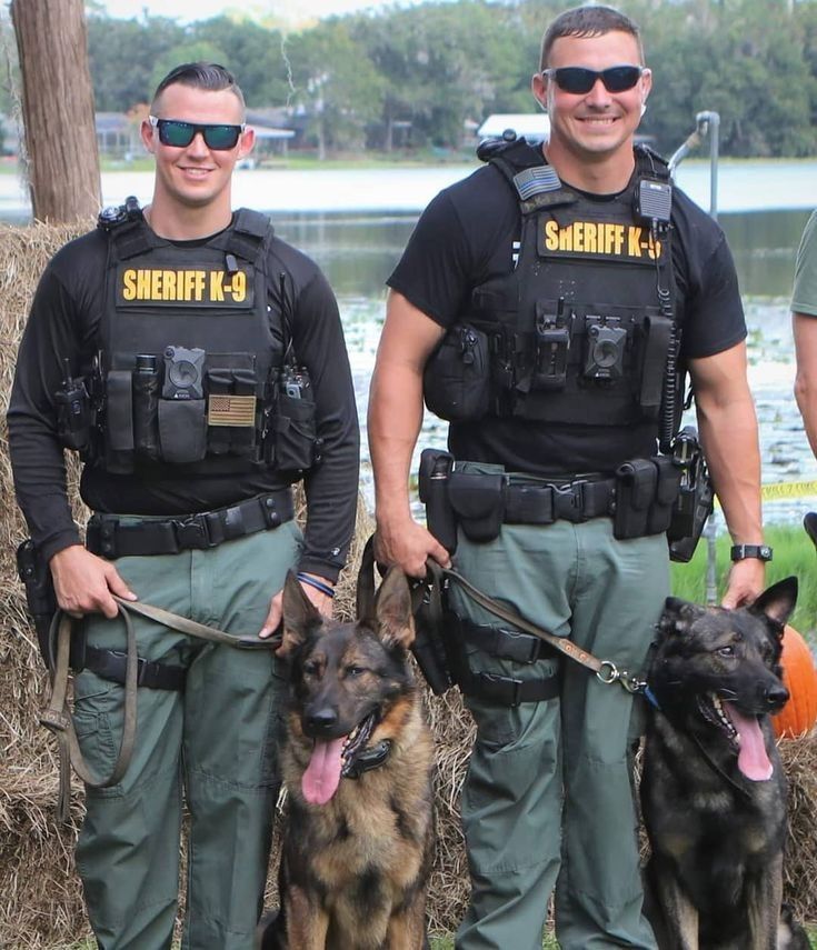 two police officers are standing with their dogs