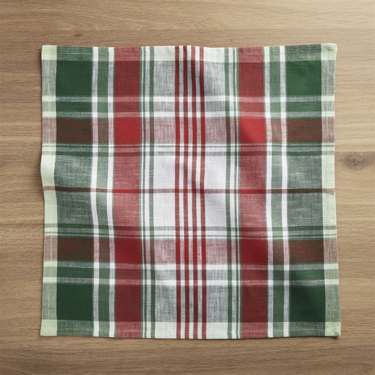 a red and green plaid napkin sitting on top of a wooden table