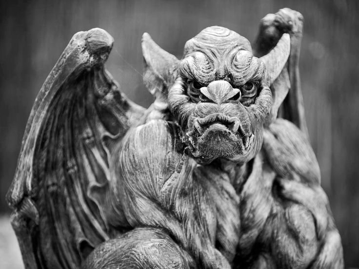 a black and white photo of a demon statue