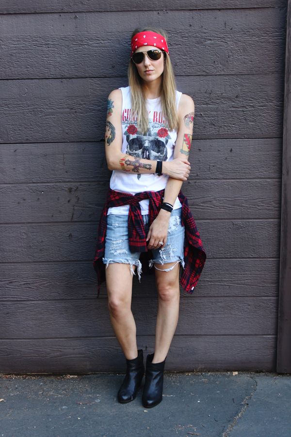 a woman with tattoos and bandana standing in front of a garage door wearing denim shorts